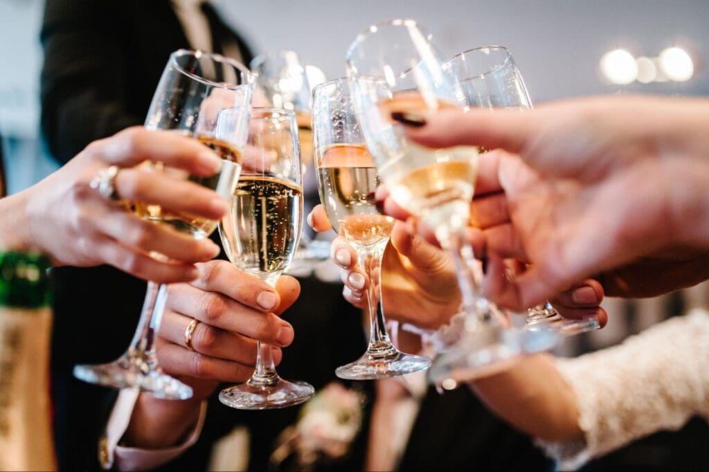 Group of people cheerfully clinking champagne glasses in a festive toast at a formal celebration.