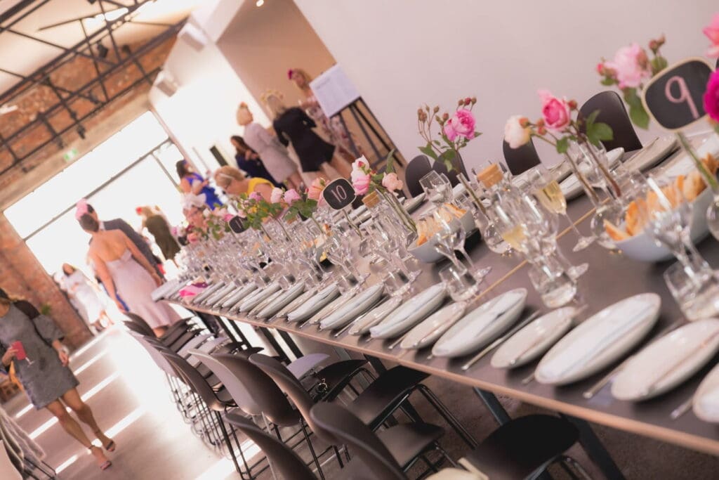 A long table set with numerous plates and glasses, ready for a wedding celebration with personalized favours for guests