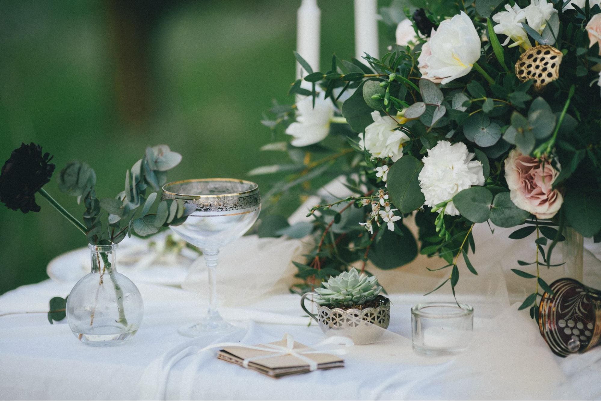 Elegant wedding table setting with lush floral arrangement, vintage glassware, and succulents, creating a sophisticated and romantic atmosphere.