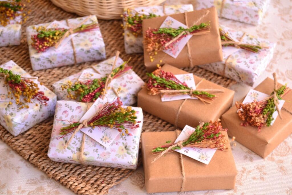 Beautifully wrapped wedding favors with floral decorations, arranged neatly on a woven mat.