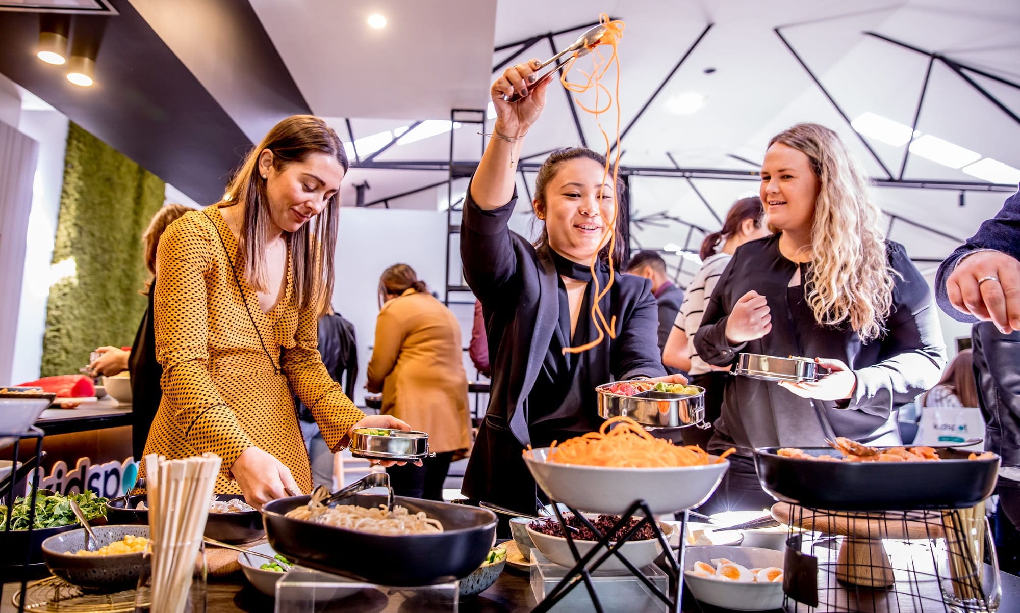 A group of guests enjoying a buffet table filled with various foods at a wedding event titled "Late Night Munchies."