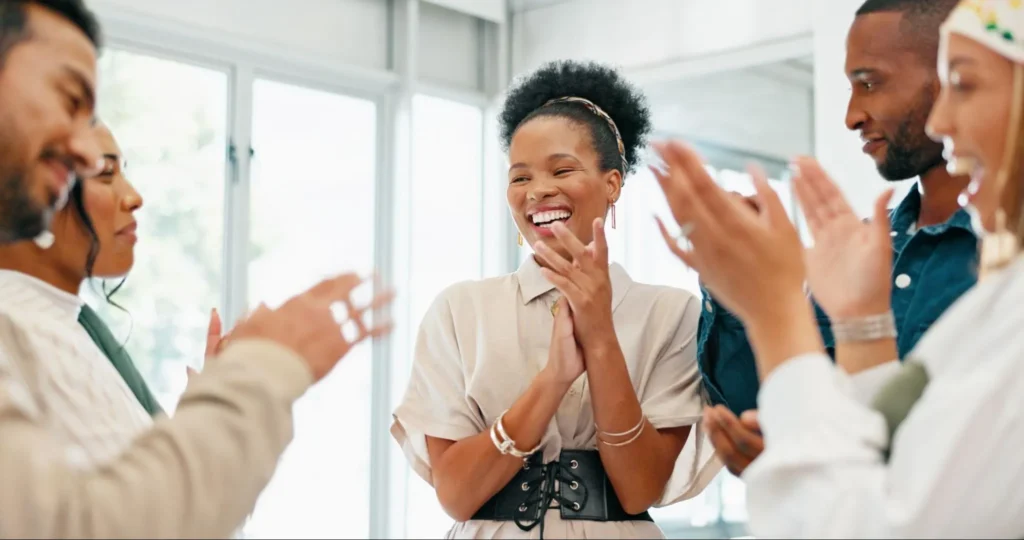 A group of colleagues clapping and celebrating a team achievement, highlighting the benefits of team building in the workplace.