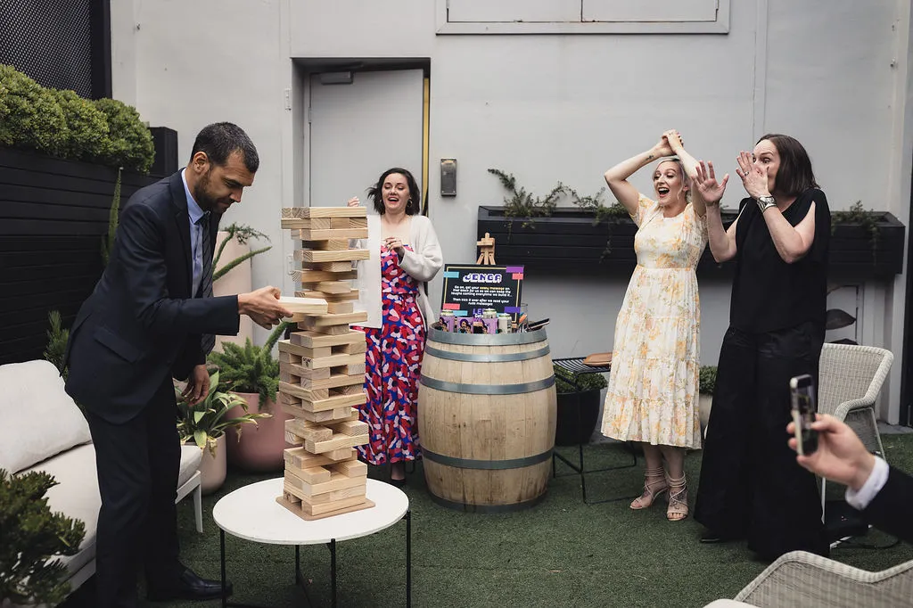 Employees playing a Jenga game as part of a team-building exercise, illustrating the purpose of team building in creating fun and collaborative experiences.