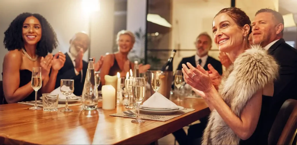 Guests clapping at a formal dinner party with candlelit ambiance