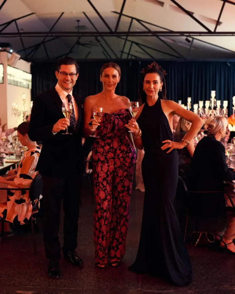 Three guests posing with drinks at a formal dinner event