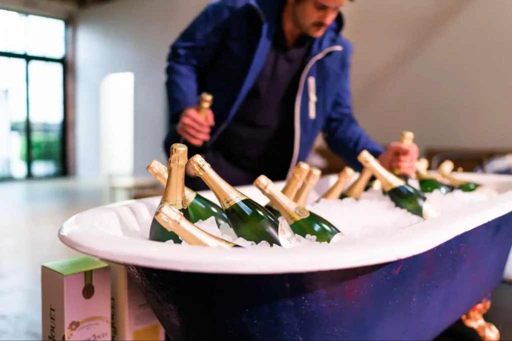 Champagne bottles chilled in a large tub filled with ice, prepared for an elegant event setup.