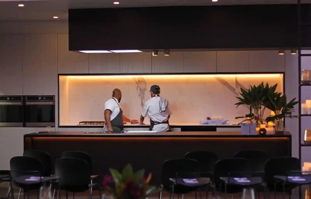 Two chefs preparing food in a sleek, modern commercial kitchen.