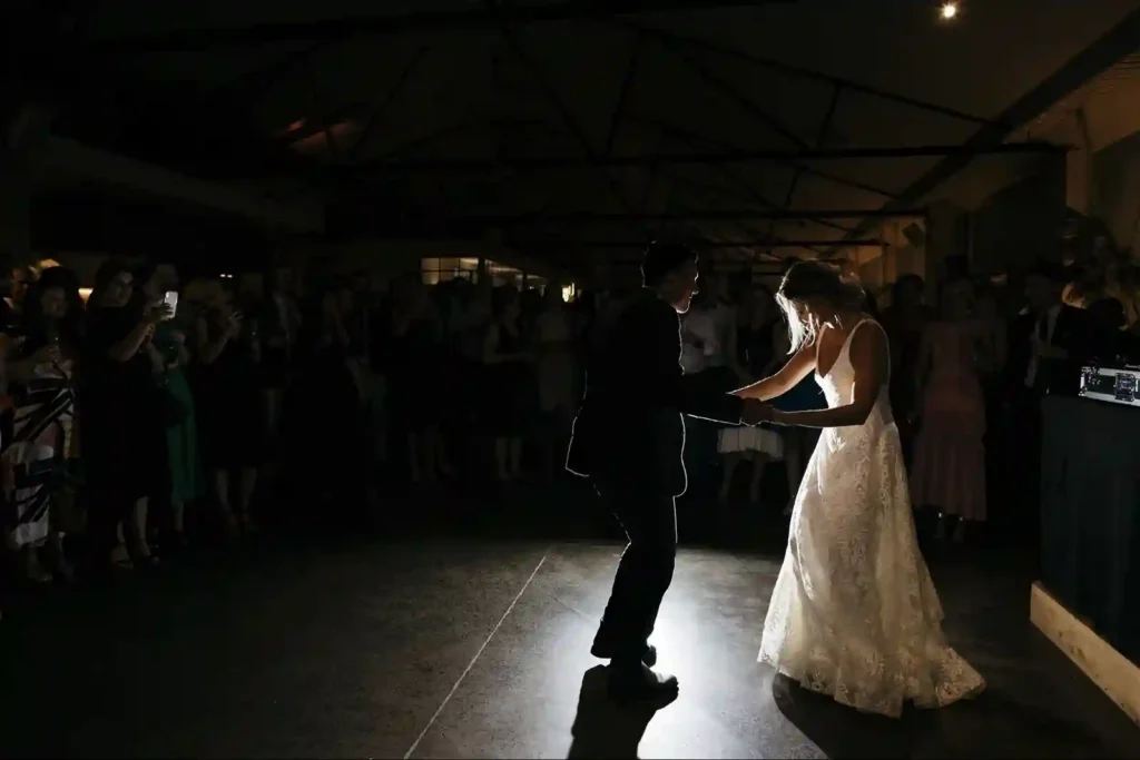 A couple sharing their first dance at a wedding reception under dim lighting.