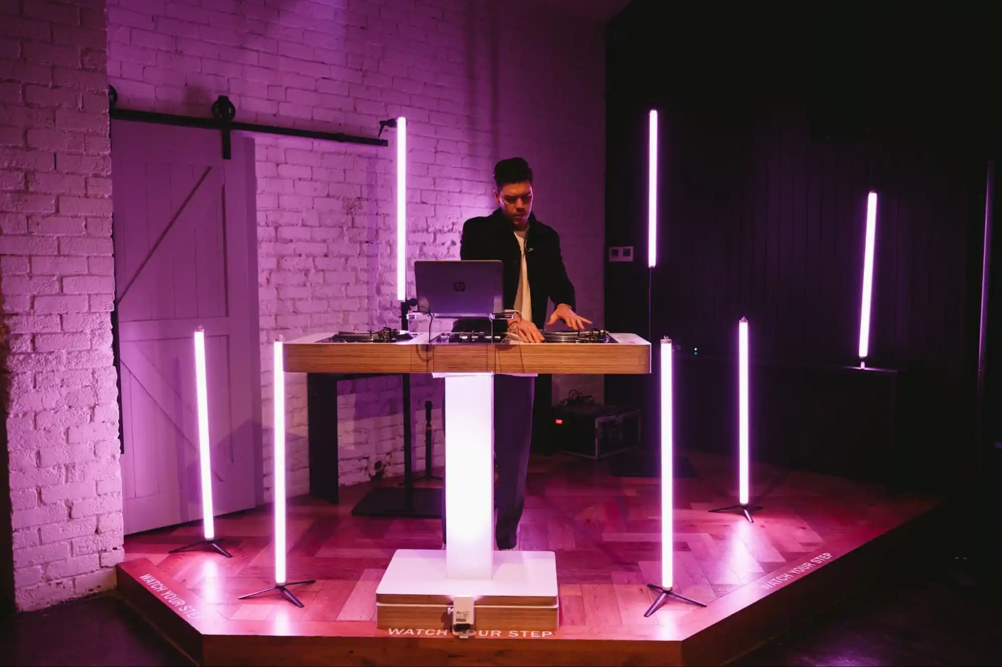 DJ performing on a stage with vibrant purple light installations.