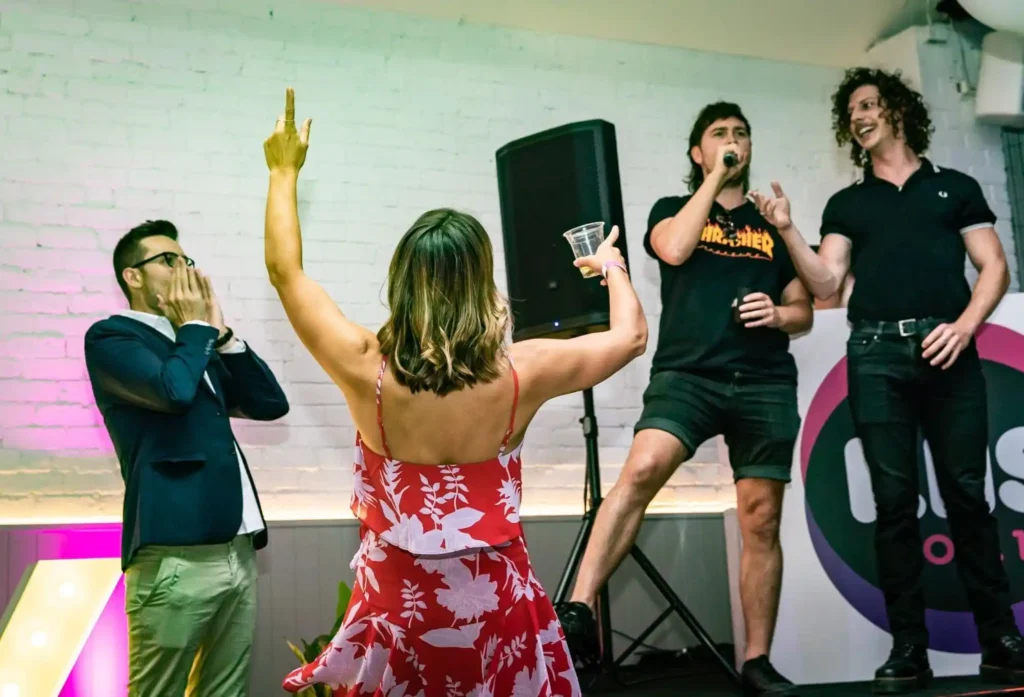 Group performing karaoke on stage while the audience cheers.