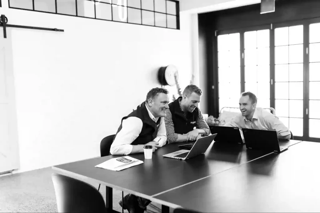 A team of three men collaborating during a meeting in a modern office setting.