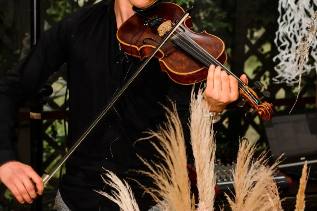 Violinist playing during a sophisticated event with pampas grass decor.