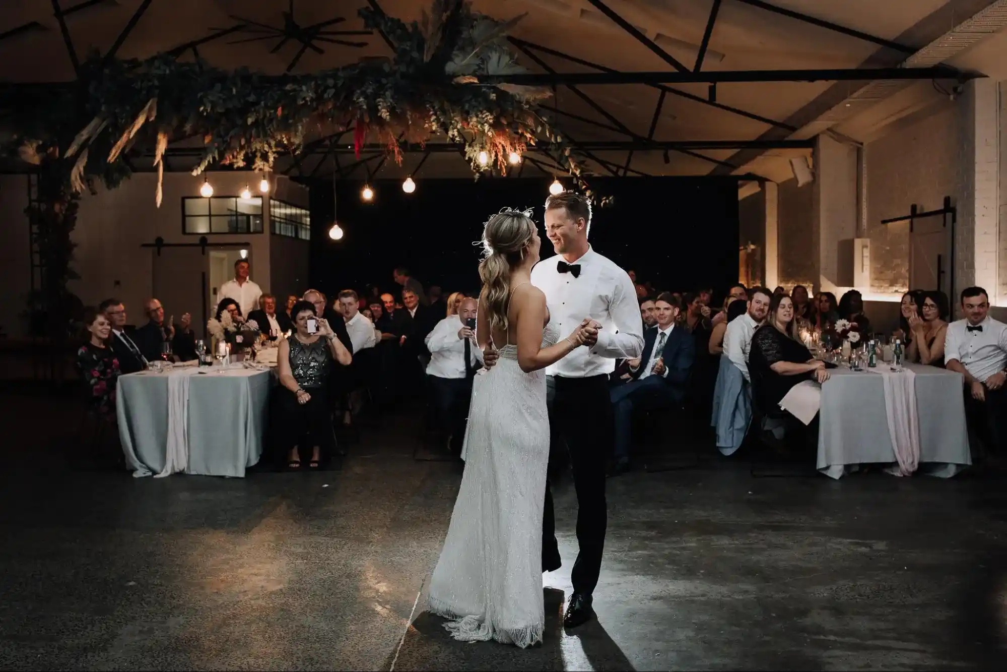 Couple dancing at a wedding reception under soft lights.