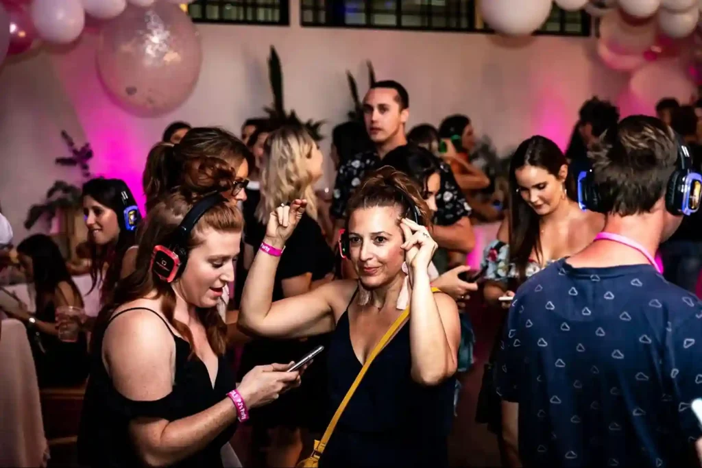 Guests enjoying a silent disco with headphones at a vibrant party.