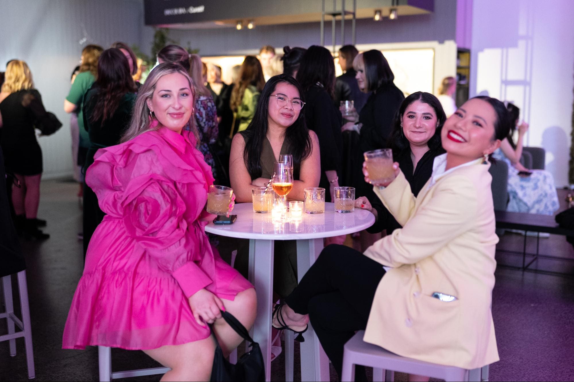 Group of women seated at a table, enjoying drinks at a social gathering.