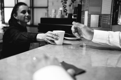 A man and woman sit at a bar, enjoying coffee together in a cozy atmosphere.