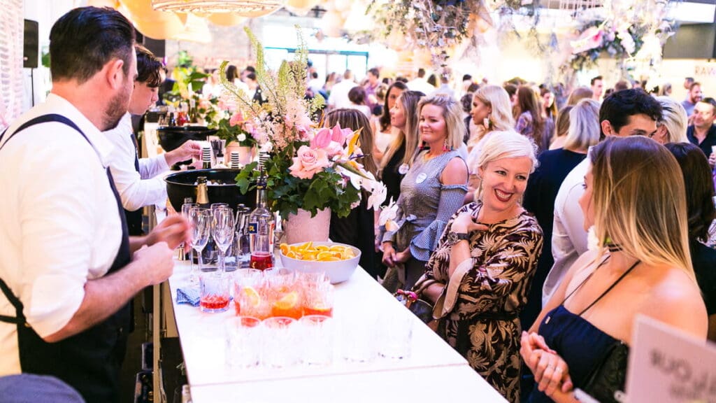 A lively crowd at a bar enjoying drinks, showcasing a vibrant social atmosphere and the trend of day-drinking.